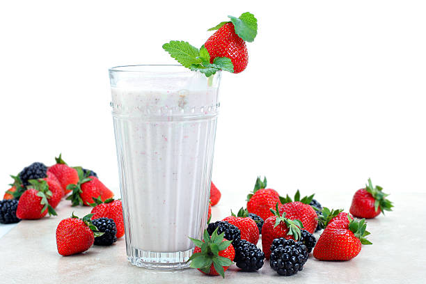 Strawberries and blackberries surround an fresh berry smoothie drink.  White background for copy space.