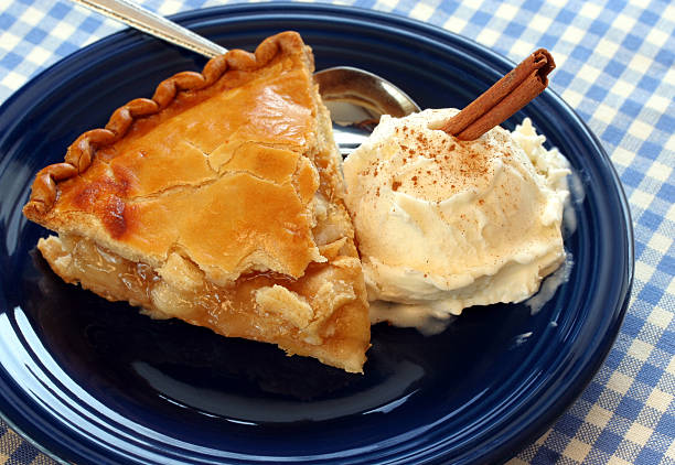Close-up of apple pie ala mode on a blue plate Fresh apple pie with French vanilla ice cream, cinnamon sprinkles and a cinnamon stick for garnish. apple pie and ice cream stock pictures, royalty-free photos & images