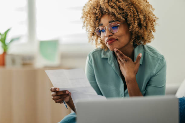 istock Portrait of a Beautiful Woman Looking at a Document While Working on her Laptop 1378158012