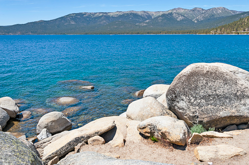 This very popular Alpine Lake includes  California and Nevada, this view shows the Nevada side with many boulders and looking across the lake to the the shore line view at edge with the heavy forest and on this June day it was  a great view.