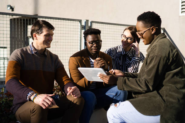 istock Young colleagues sitting outside and looking at digital tablet 1378187118
