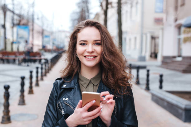 Focused woman walking and texting message on smartphone in city stock photo