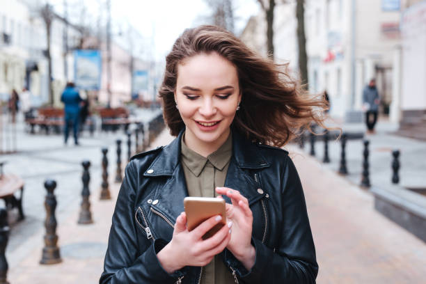 istock Focused woman walking on sidewalk and reading message on smartphone 1378196553