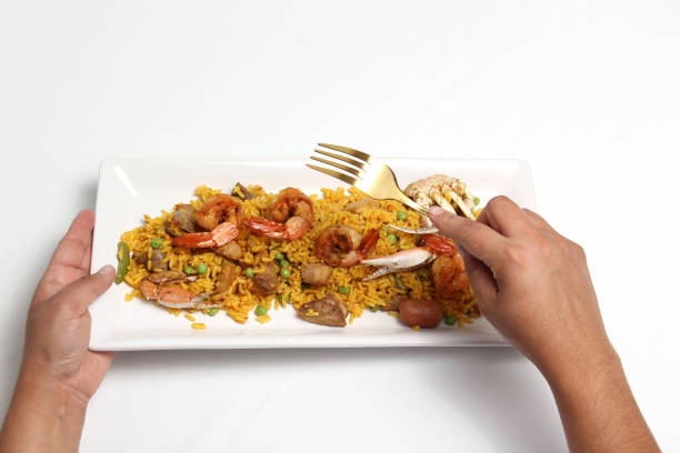 Paella rice is a dish from the Spanish city of Valencia, hands served on a white restaurant plate or made at home with saffron, shrimp, sausage, seafood