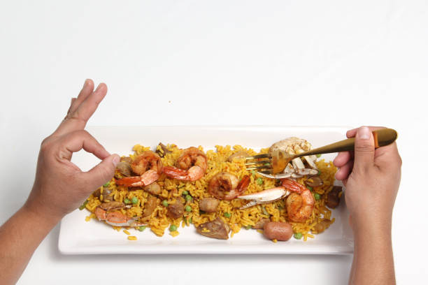 Paella rice is a dish from the Spanish city of Valencia, hands served on a white restaurant plate or made at home with saffron, shrimp, sausage, seafood