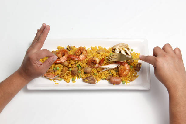 Paella rice is a dish from the Spanish city of Valencia, hands served on a white restaurant plate or made at home with saffron, shrimp, sausage, seafood