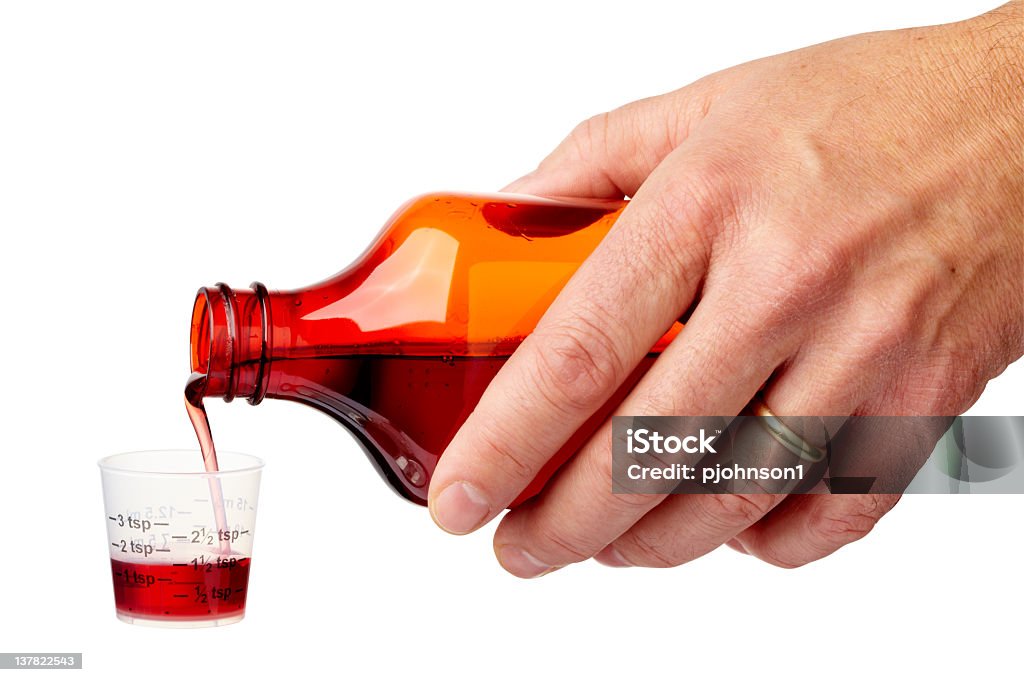 Kids medicine Hand pouring cough medicine into a graduated cup.  Larger files come with clipping path. Aspirin Stock Photo