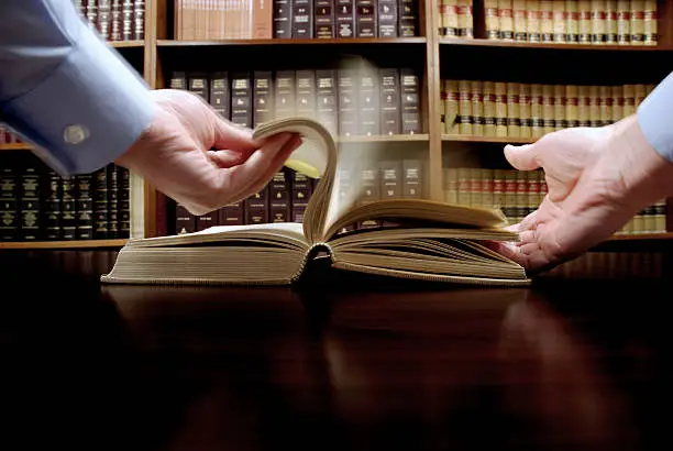 Hands flipping pages in book in library