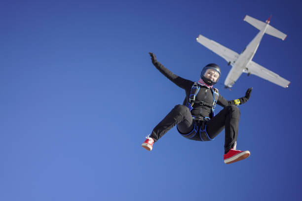 Female skydiver falls out of airplane, aerial flight She falls through a blue sky over the Swiss Alps, in the sunshine skydiving stock pictures, royalty-free photos & images
