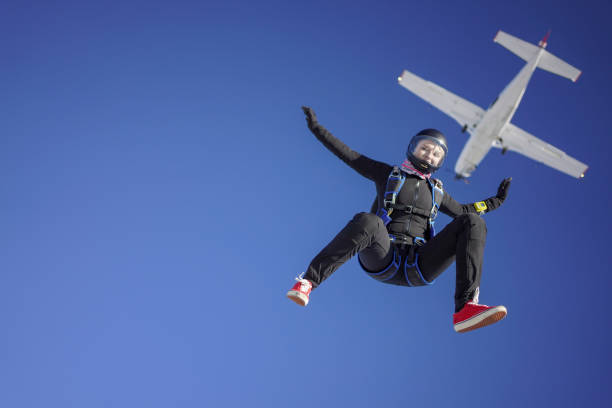 female skydiver falls out of airplane, aerial flight - freefall imagens e fotografias de stock