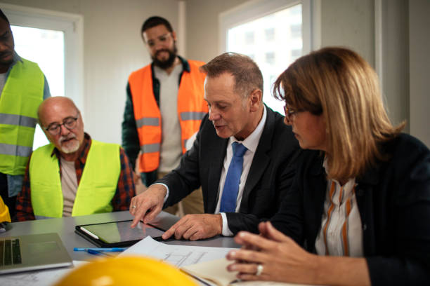 There are regulations we must comply with Board directors having a meeting with the team in the office at the construction site blue collar worker stock pictures, royalty-free photos & images