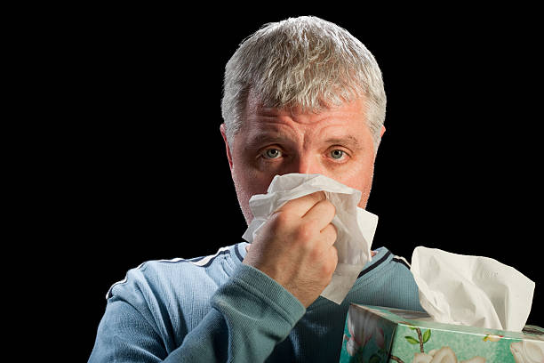 man blowing his nose with tissue stock photo