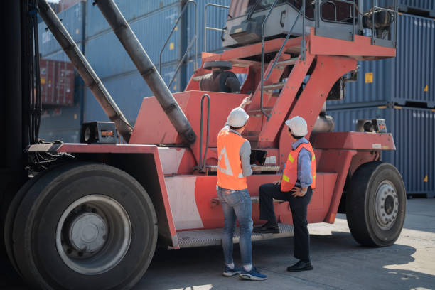 istock factory worker people men standing in front of containers logistic in warehouse. workers inspecting and meeting in front of heavy machine vehicle car. 1378288171