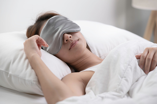 Young woman with eye mask sleeping in her bed and relaxing in the morning