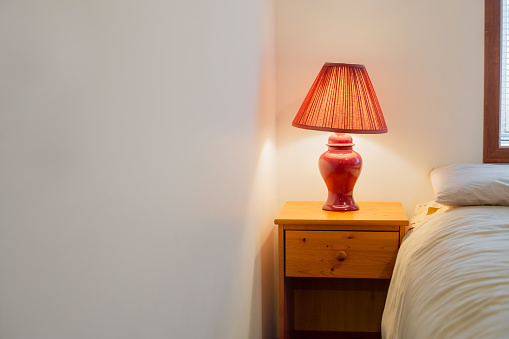 A red lamp on a bedside table in a 90s-themed bedroom
