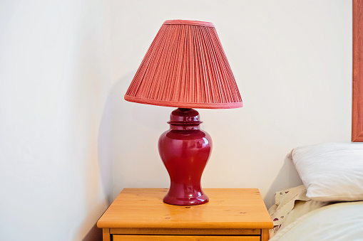 A red lamp on a bedside table in a 90s-themed bedroom