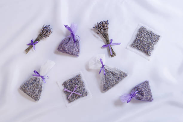 DIY lavender sachets for home, ideas for gifts, transparent package with natural scented dried flowers, white lavender colored silk cloth on table. Aromatherapy and herbal medicine concept. Top view
