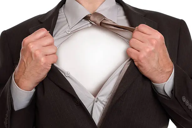 Businessman in classic superman pose tearing his shirt open to reveal blank copy space on chest