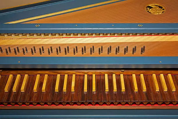 Blue open harpsichord with dark and light wooden keyboard; selective focus on the keys.