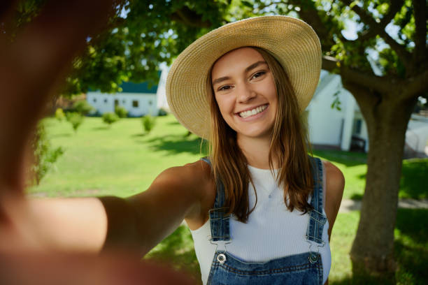 Caucasian female farmer working outdoors taking selfie with cellular device
