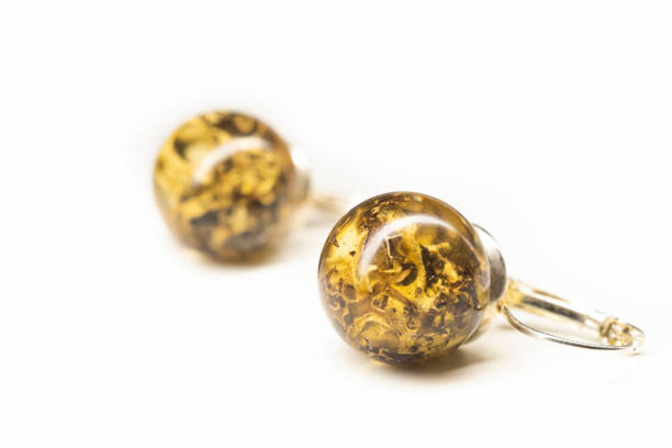 Organic lichen preserved in epoxy resin earrings. Natural handmade jewelry. Sphere ball shape, glossy surface. Selective focus on the details, object isolated on white background.