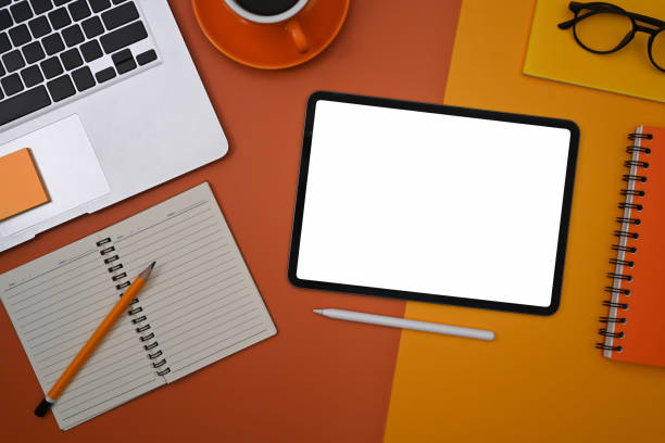 istock Top view digital tablet, laptop, coffee cup and notebook on orange background. 1378623039