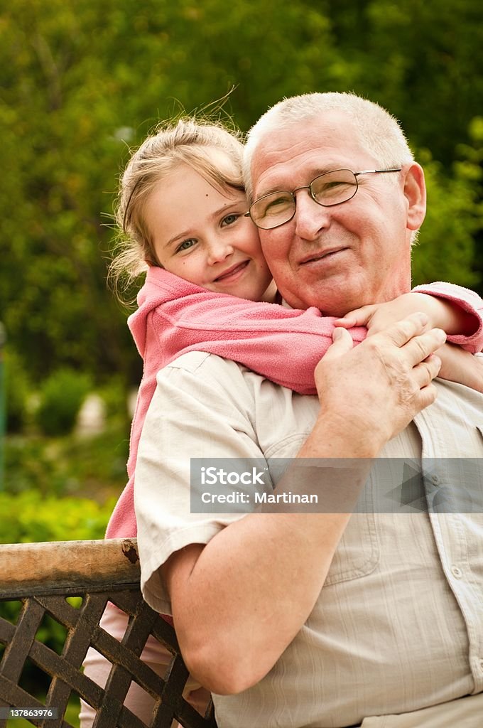 Filha abraçando seu avô de trás - Foto de stock de Avô royalty-free