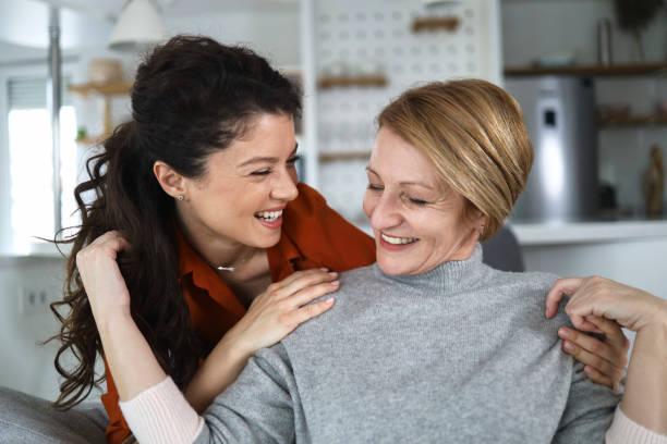 Happy adult daughter and old mom relax at home stock photo