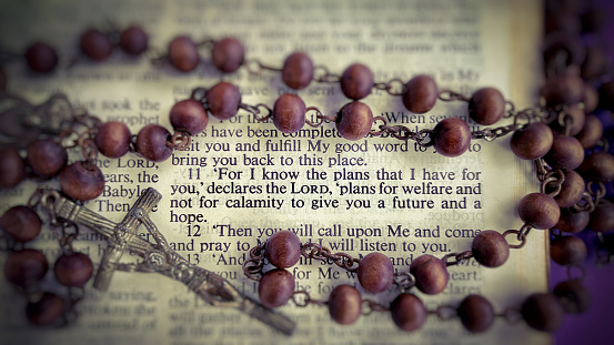 Top view of Bible verses with blurred Holy Rosary Background. Christianity concept