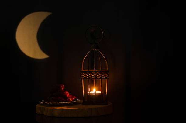 istock Lantern and small plate of dates fruit on wooden tray with moon shape from light on background 1378685795