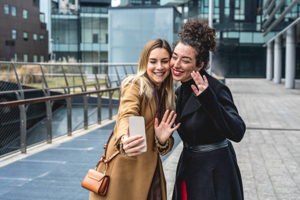 istock two young women greeting in a video call theri friends, people using technology and app web for keeping touch with relatives and other people, break in the city with colleagues 1378687486