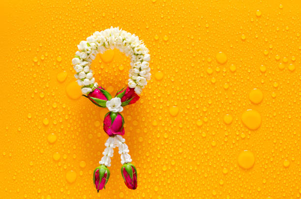 Jasmine garland puts on clear mirror that have wet yellow background below for Songkran festival concept.