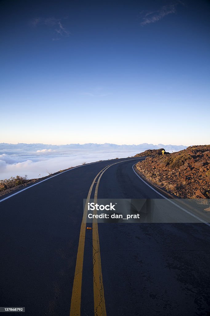 Road to Heaven A mountain road high above the clouds with a light blue sky. Asphalt Stock Photo