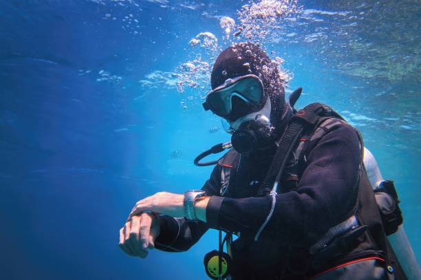 voll ausgestatteter männertaucher unter wasser im blauen wasser - deep sea diving stock-fotos und bilder