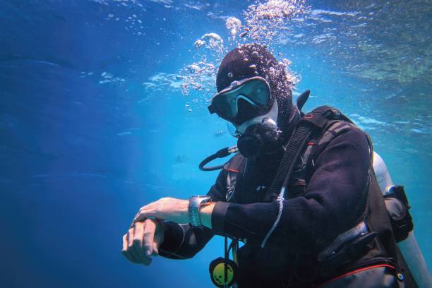 青い水の中で水中で完全装備の男スキューバダイバー - scuba diving ストックフォトと画像