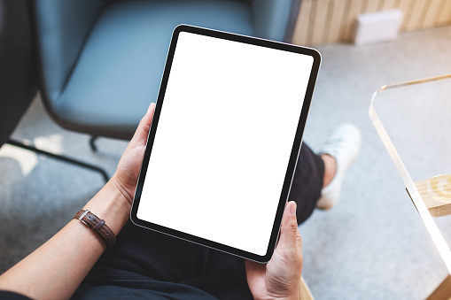 Imagen de maqueta de una mujer sosteniendo una tableta digital con una pantalla de escritorio blanca en blanco en un café photo