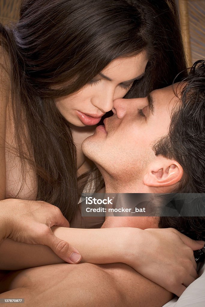 Young naked Man and woman in love are kissing Loving affectionate nude heterosexual couple in affectionate sensual kiss. Mid adult Caucasian men in late 30s and young Hispanic woman in early 20s Couple - Relationship Stock Photo