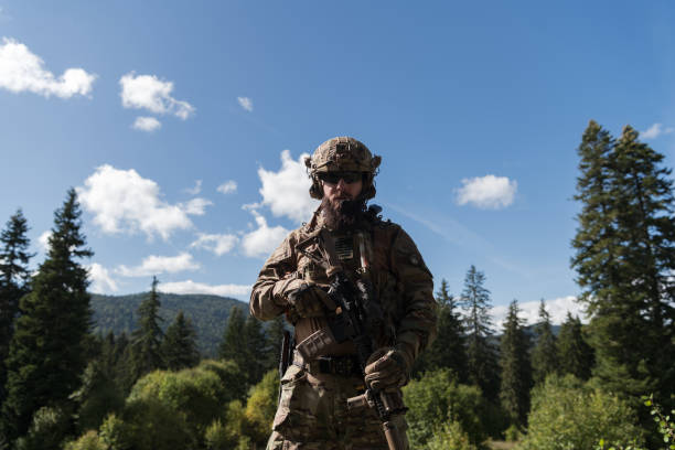 istock War concept. A bearded soldier in a special forces uniform fighting an enemy in a forest area. Selective focus 1378740058