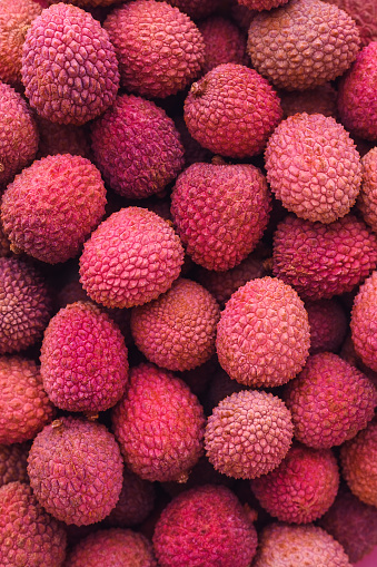 many ripe red unpeeled lychees - vertical food background