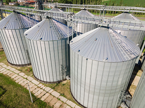 Metal tanks of elevator. Grain-drying complex outdoors. Commercial grain silos and steel storage for agricultural harvest.