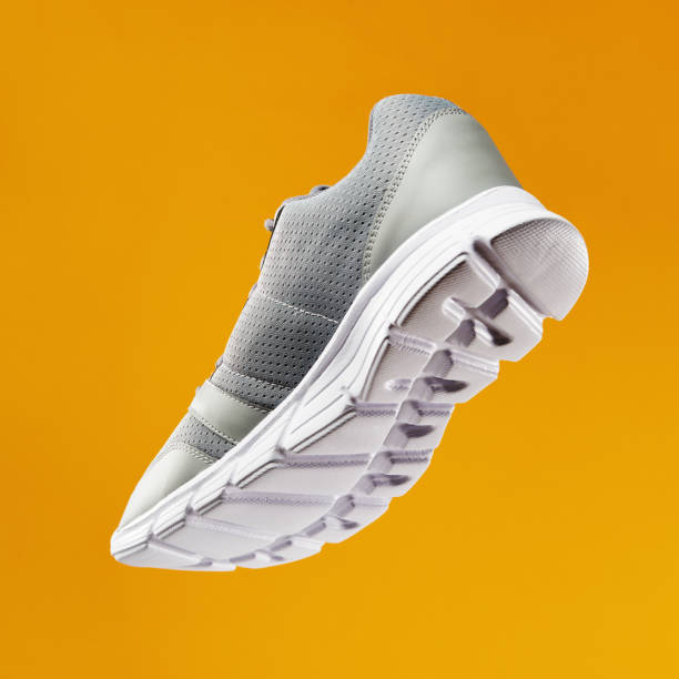 Low angle bottom view of sports running and fitness shoe, sneaker on orange background Low angle bottom view of sports running and fitness shoe, sneaker on orange background sole of shoe stock pictures, royalty-free photos & images