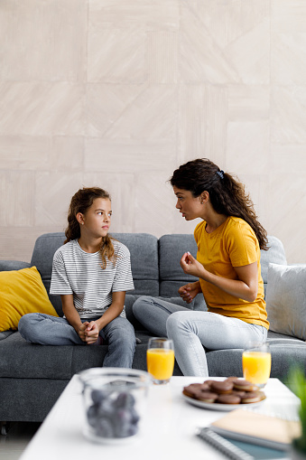 Young mother feeling worried while communicating with her daughter in the living room. Copy space.
