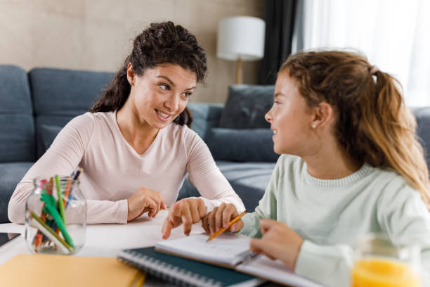 istock Happy mother helping her daughter with studying at home. 1378759513