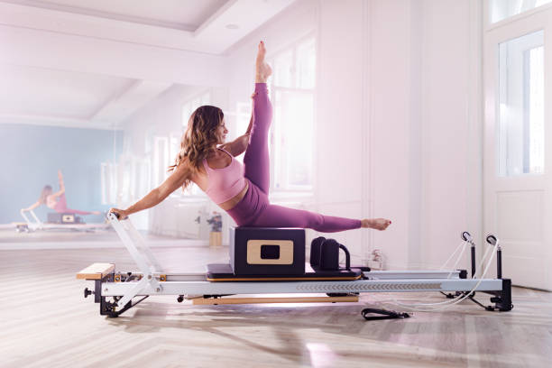 istock Smiling athletic woman stretching on a Pilates machine. 1378769931