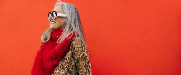 istock Happy grey-haired woman smiling cheerfully against a red background 1378772124