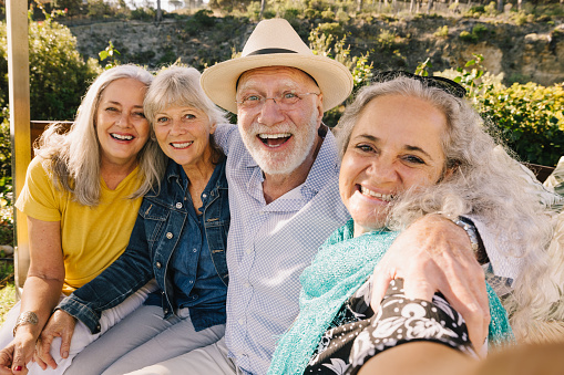 Excited senior friends taking a selfie together during vacation. Cheerful elderly people enjoying a weekend getaway at a spa resort. Group of happy senior citizens having fun after retirement.