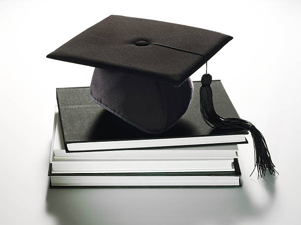 sombrero de graduación en libros - yearbook fotografías e imágenes de stock