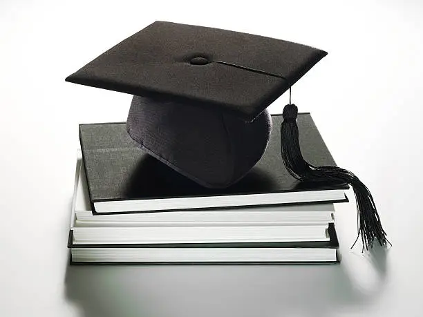 Academic cap with tassel on stack of books.