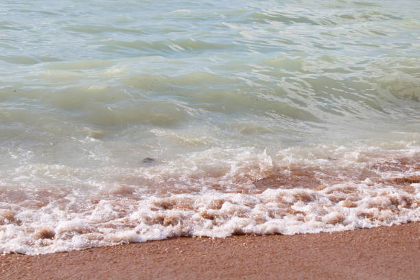 Nature of beach and blue water, summer with sunshine, sandy beach Sparkling sea water. Beach sand background for summer vacation concept