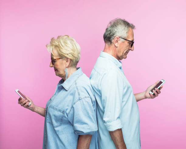 istock Senior couple standing back to back using phones 1378804403